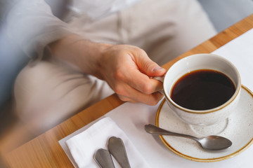 Male hand holding white cup of coffee