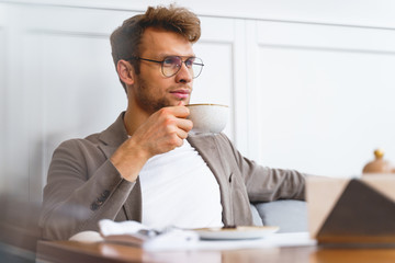 Handsome young man drinking coffee in cafe