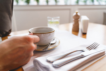 Male hand holding white cup of coffee