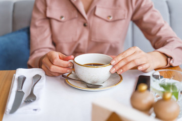 Female hands holding white cup of coffee