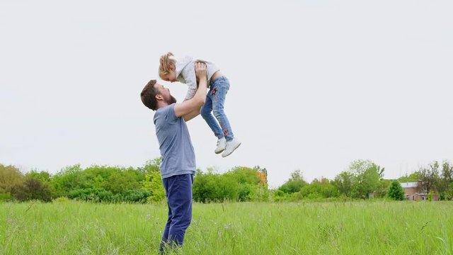 dad playing with daughter in the field, toss up.