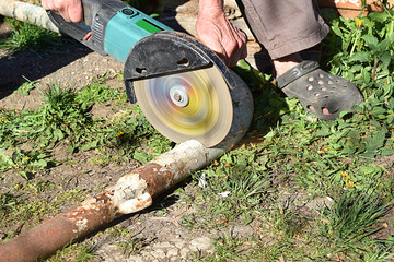 worker cuts steel pipe with angle grinder