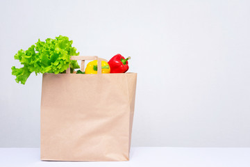 Vegetables in shopping paper bag, kitchen table, side view, white background, copy space