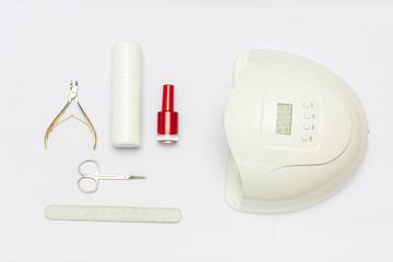 Uv-lamp for gel nails polish, red nails polish and manicure supplies, white background, copy space, top view