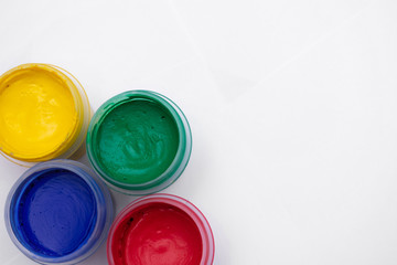 Cans of different colors gouache paints, top view, closeup, white background, copy space