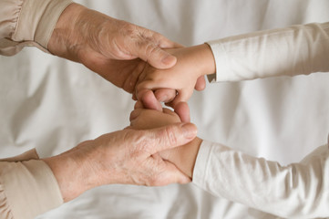 Hands of a child in the hands of an old woman on a white background. Family bonds,