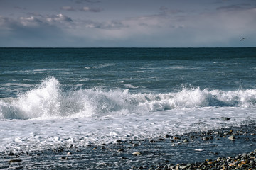 On a sunny day, a storm in the sea wave breaks on the shore. Winter sea beautiful landscape