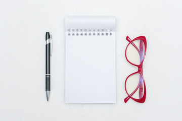 Notepad, pen and red women's glasses, white background, top view, copy space