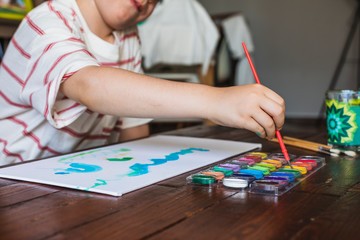 Naklejka premium A boy paints a picture with his watercolors at home due to confinement by Covid-19.