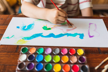 Naklejka premium A boy paints a picture with his watercolors at home due to confinement by Covid-19.