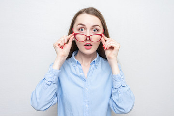Shocked nerd in red glasses looks at the camera, portrait, white background