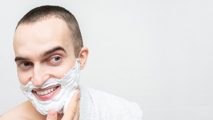 Cheerful guy with shaving foam on his face, white background, 16:9, copy space