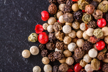 mix of peppercorns on a dark stone background