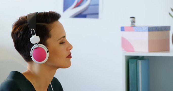 Side view of businesswoman in headphones working on computer at desk