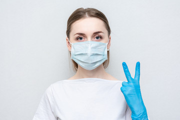 Nurse in medical mask and gloves show sign two, portrait, close up