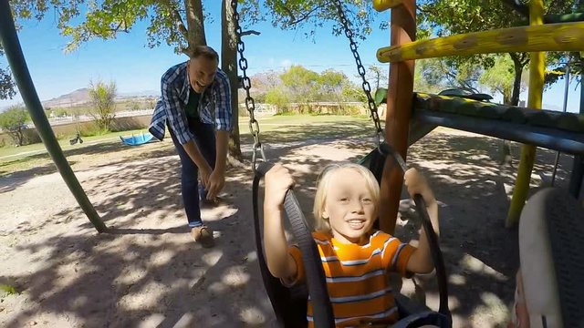 Father pushing son on swing in the park