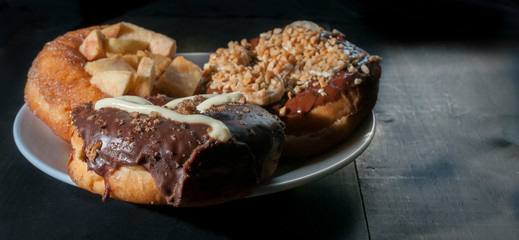 Chocolate donuts on a white plate and on a wooden rustic table