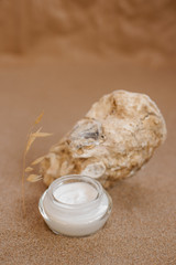 Fototapeta na wymiar Caring cosmetics in an oyster shell on the sand. Eco-friendly organic cosmetics.