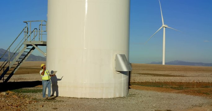 Male engineer talking on mobile phone while using laptop in the field