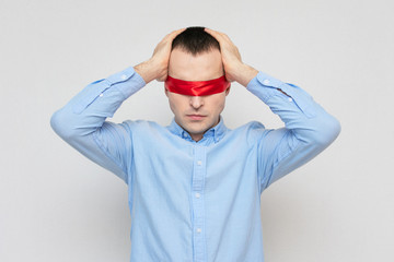 Man can't solve a difficult task, red blindfold, guy grabbed his head,  portrait, white background
