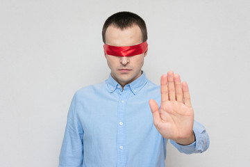 Man with a blindfold shows a stop sign, red blindfold, portrait, white background, copy space