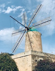Old windmill surrounded by bushes on sky background