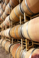 looking down rows of oak wine barrels on metal storage racks in warehouse