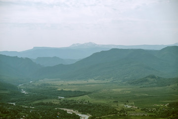 Naklejka premium mountain village far away mountains visible in midday haze hot sunny day humid climate