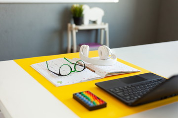 laptop, glasses, headphones, a notebook lie on the desk, desk of a modern schoolboy, concept of online school, education on the Internet