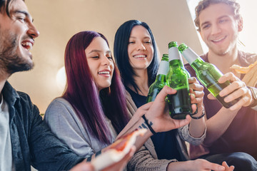 Group of young friends with pizza and bottles of beer celebrating