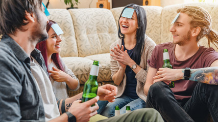 Happy group of friends with sticky notes on foreheads playing name game with beer
