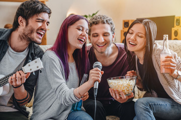 Group of friends having party together at home while singing - obrazy, fototapety, plakaty