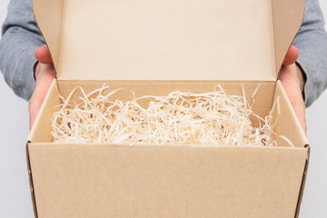 Man opens gift box with decorative shavings, men's hands, closeup