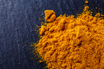 natural turmeric powder on a dark stone background
