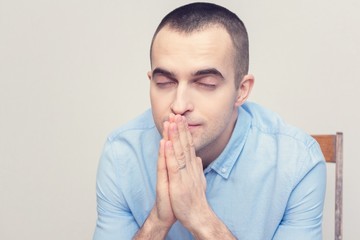 Young man prays sitting down, portrait