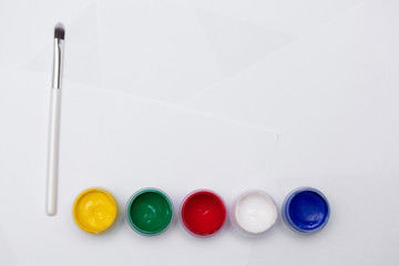 Cans of different colors gouache paints and artist brush, white background, copy space