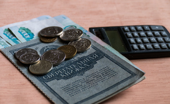 Savings with rubles and calculator on a brown table