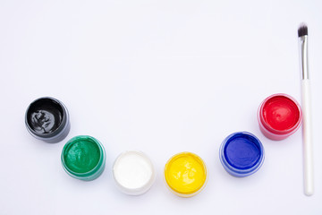 Gouache paints of different colors and artist brush, white background, copy space