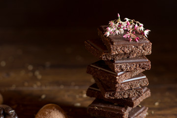 Torre de chocolate con flor decorativa y nueces sobre mesa de madera