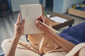 Talented female artist drawing in notebook at home