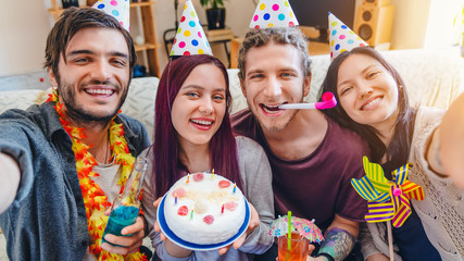 Happy friends with birthday party accessories taking selfie and having fun