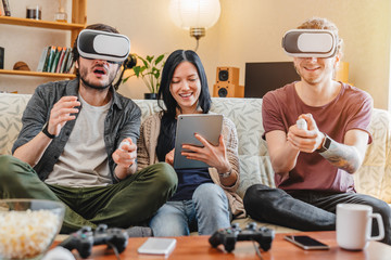Happy friends having fun with VR googles at home interior