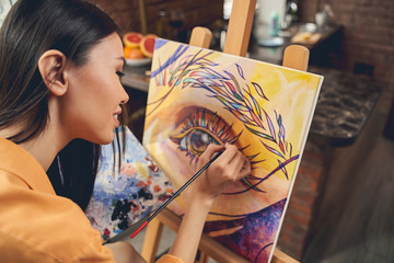Beautiful female artist drawing picture with paints