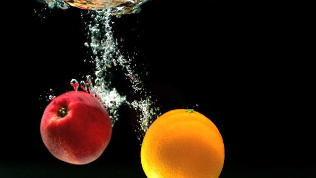 Apple and orange falling in water