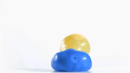 Yellow balloon rebounding in super slow motion on a blue one - Powered by Adobe