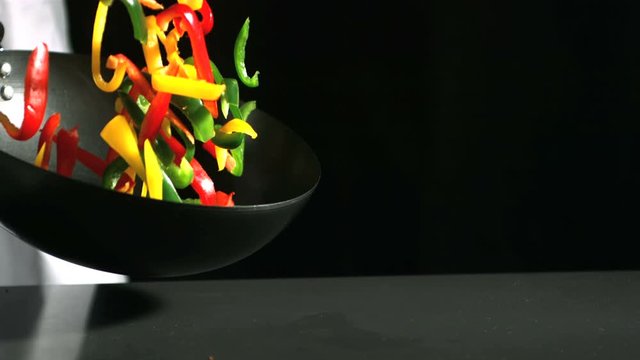 Chef tossing wok of peppers