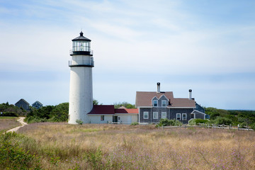 Fototapeta na wymiar Highland Lighthouse on the east coast of the United States stands tall as a white tower over ocean as a beacon of safety. 