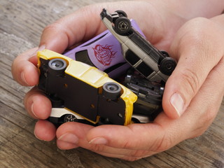Children's toy cars lie in the hands of a person. Small cars lie in the hands of a person.
