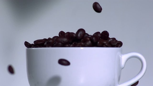 Overflowing coffee beans in a white cup