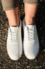 female legs in white moccasins on the nature, concept of summer shoes and outdoor recreation.